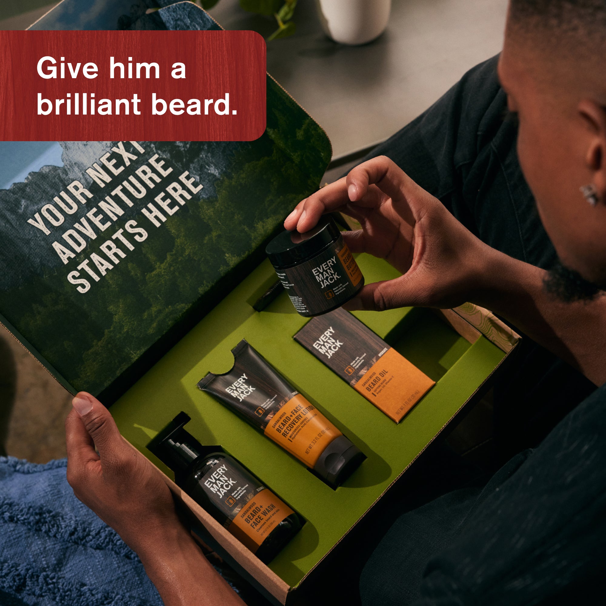 A man holding a beard gift set with products displayed in a box, featuring the text 'Give him a brilliant beard.'