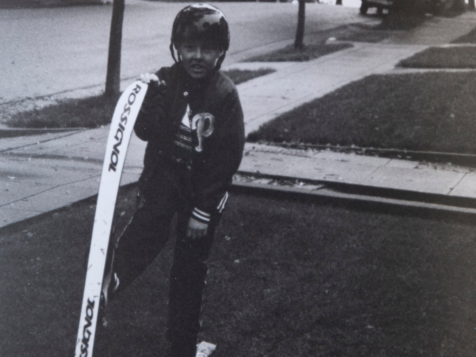 Young Connery Lundin posing with skis on a suburban street