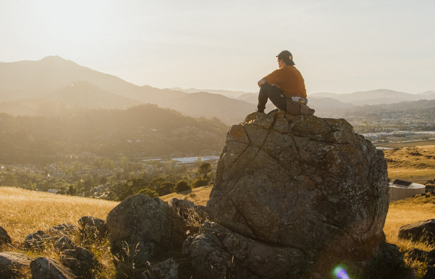 Athlete sitting on rock looking at sunset