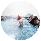 A person relaxing in a hot spring surrounded by rocks.
