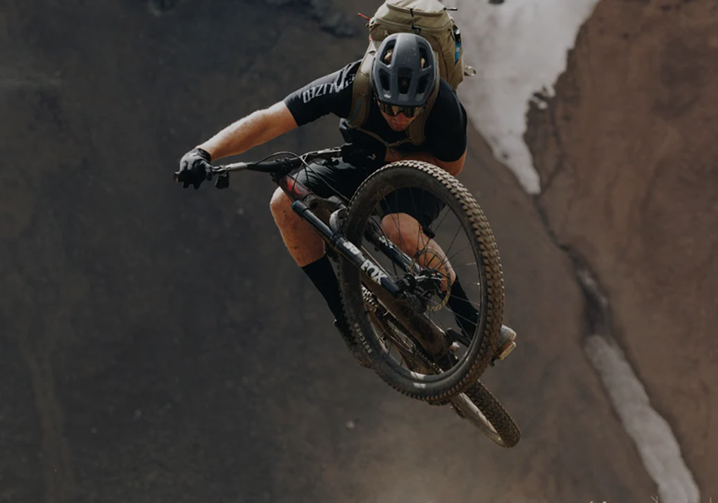Mountain biker mid-air performing a jump against a rocky canyon background