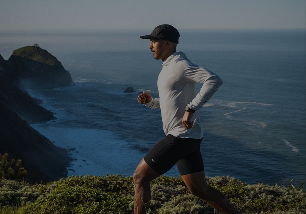 Dezmond Taylor-Douglas running along a grassy coastal cliff with the ocean in the background