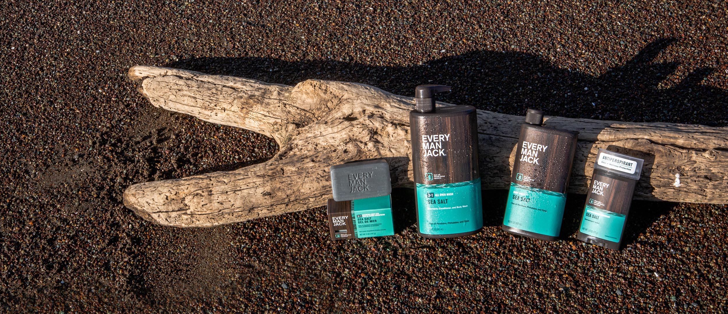 Every Man Jack grooming products including shampoo, conditioner, and body wash on a wooden surface.