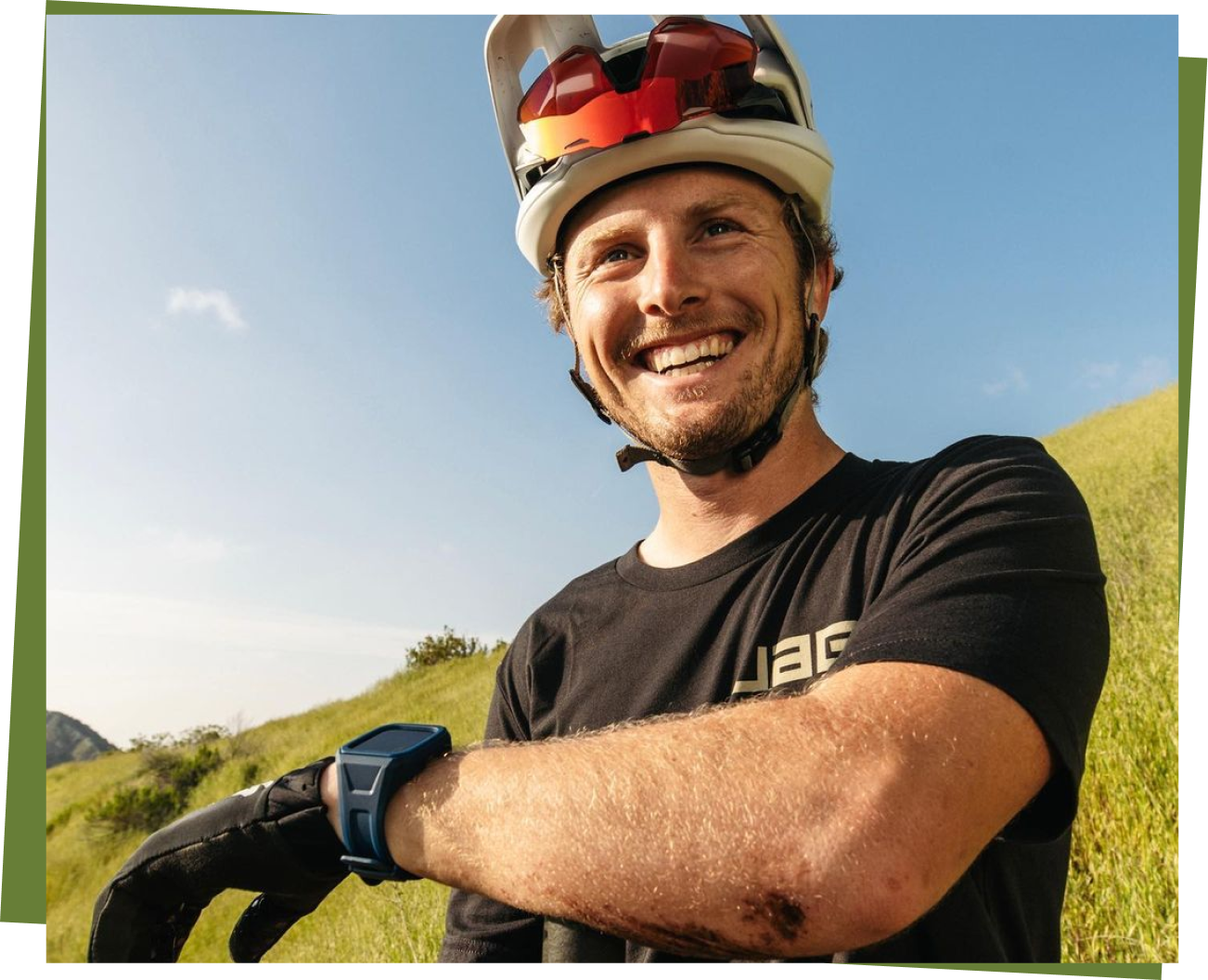 Spencer Rathkamp smiling in biking gear on a grassy hill
