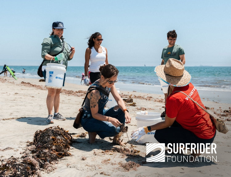 Participants cleaning a beach for the Surfrider Foundation, collecting debris and engaging in environmental conservation.
