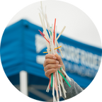 A hand holding colorful straws during a beach cleanup event.