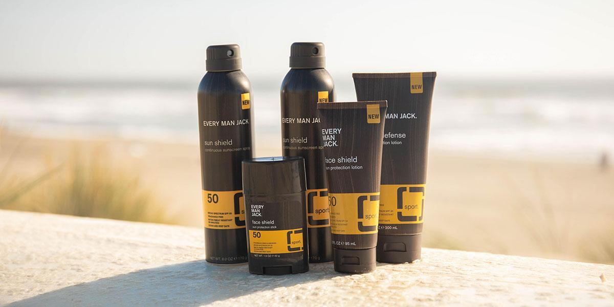Front view of Every Man Jack sun care products showcasing sun shield and face shield packaging on a beach