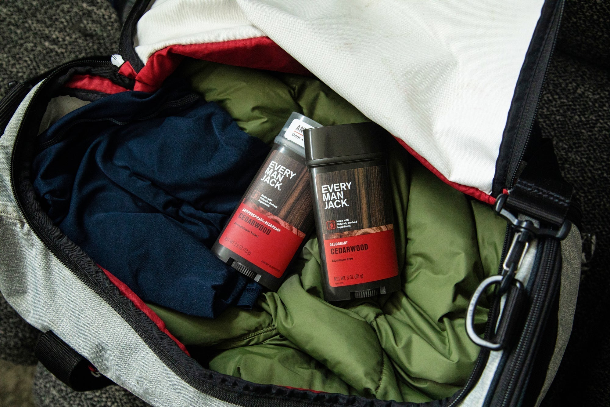 Two Every Man Jack deodorant products in a duffel bag, one Cedarwood scent.