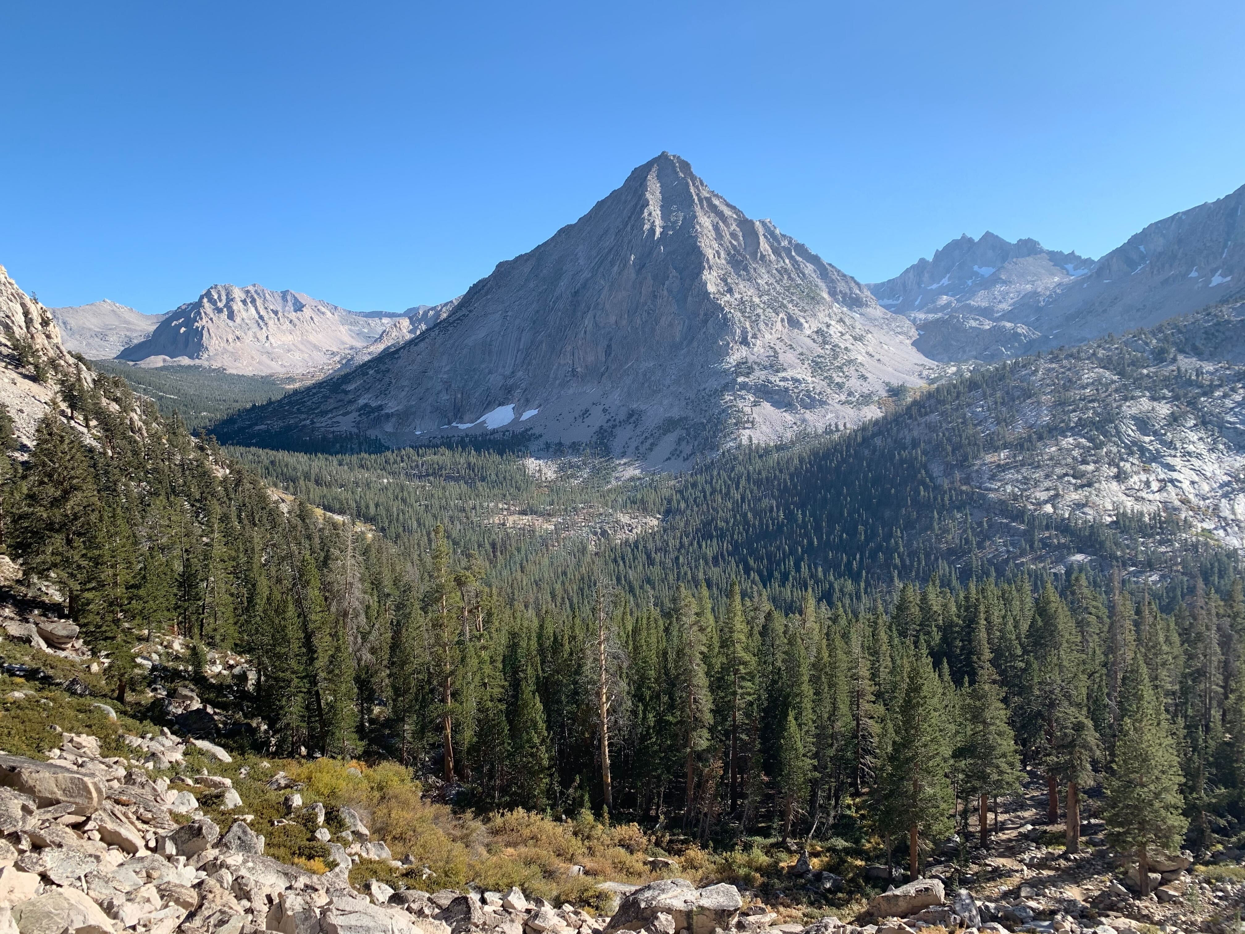 A scenic view of a mountain range with trees in the foreground.