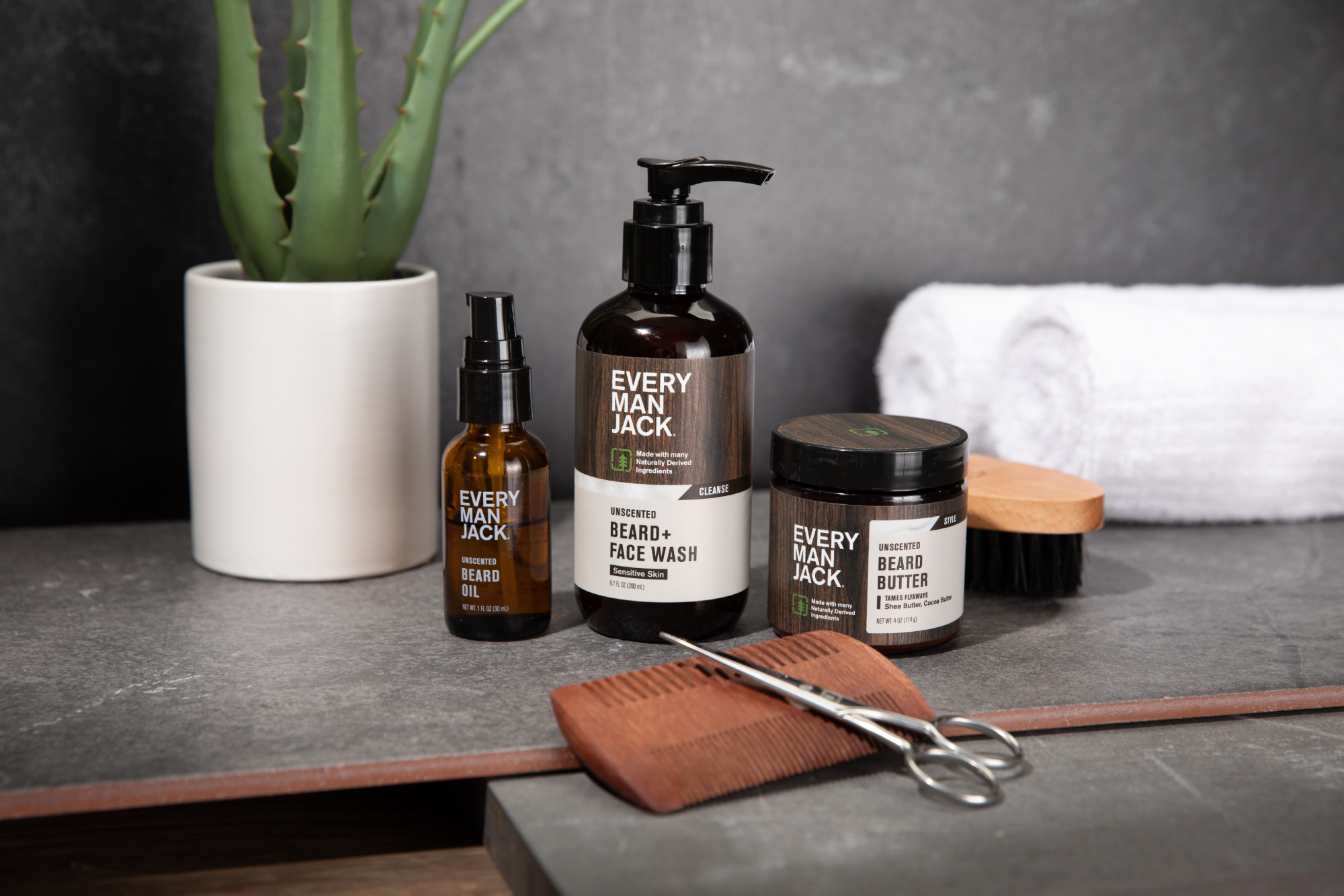 A collection of Every Man Jack beard care products including beard wash, beard oil, beard butter, and a comb.