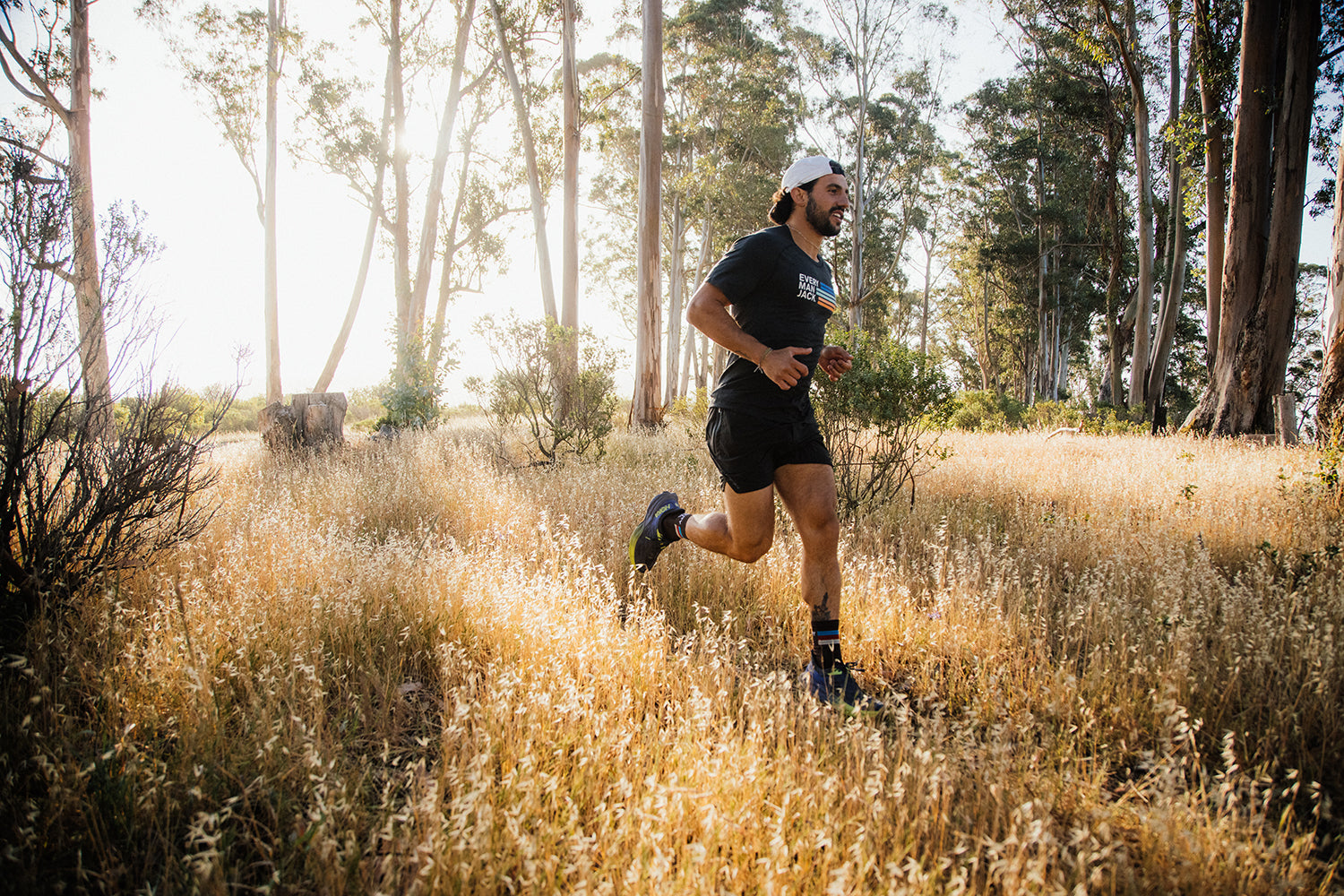 A man running through a field of tall grass in a forested area.