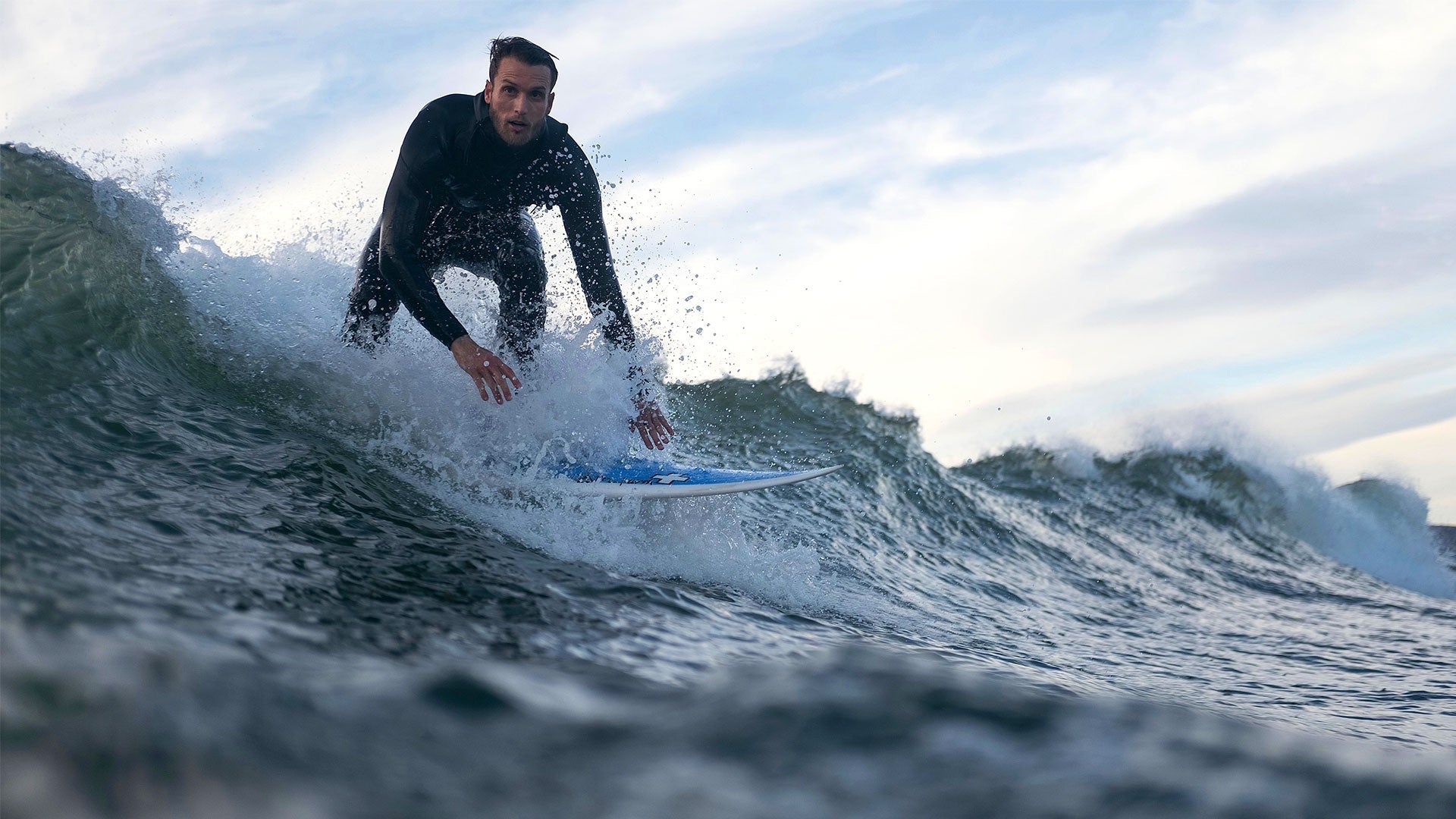 Surfer Nolan Koon riding a wave in the ocean at sunset