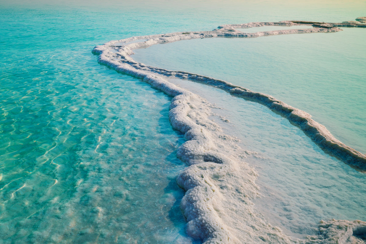 Coastline with salt deposits and clear blue water.