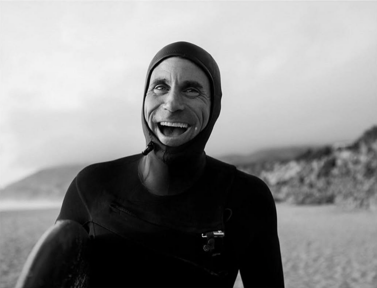 Chris Sheirholtz wearing a wetsuit with a hood on a beach