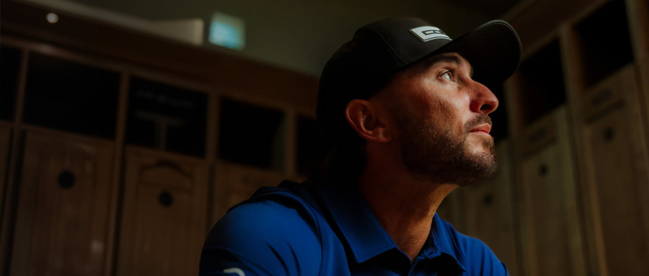 Max Homa wearing a blue shirt and black cap in a locker room