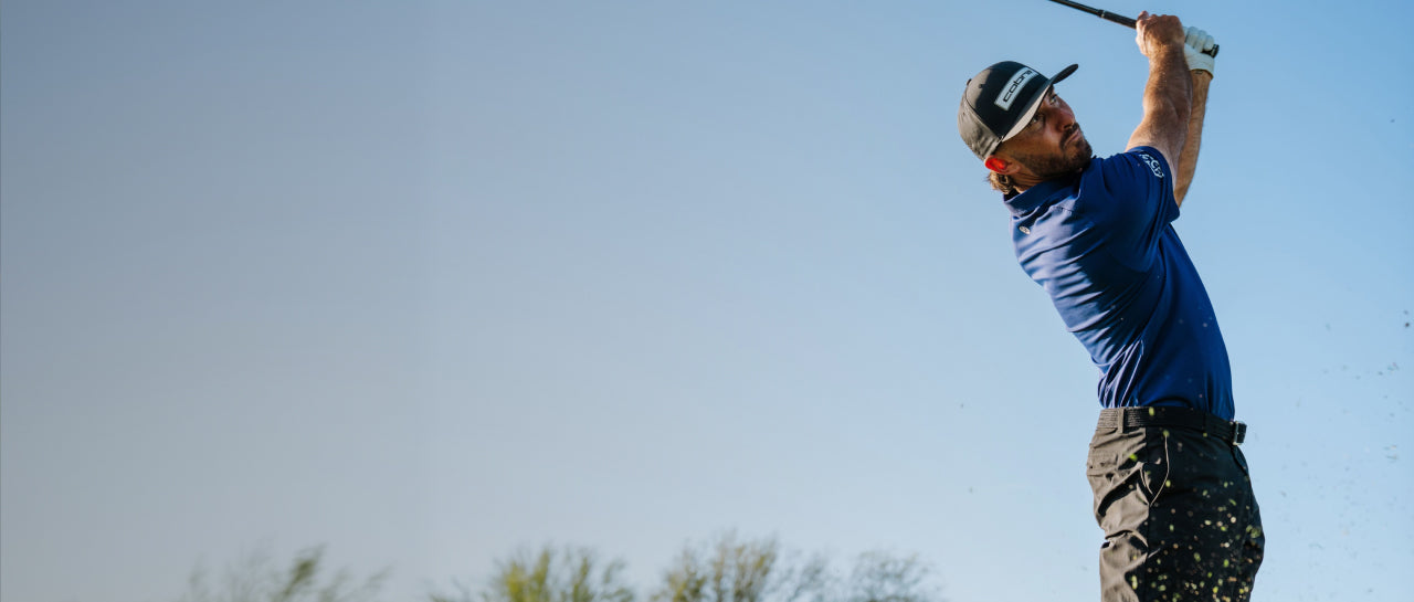 Max Homa in mid-swing against a clear blue sky