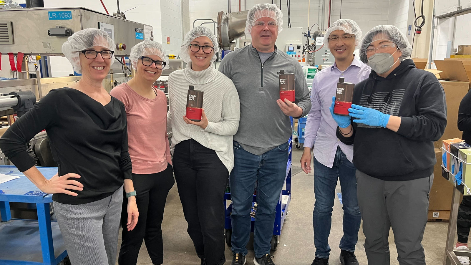 Quality Control Team at Every Man Jack holding products in a factory setting