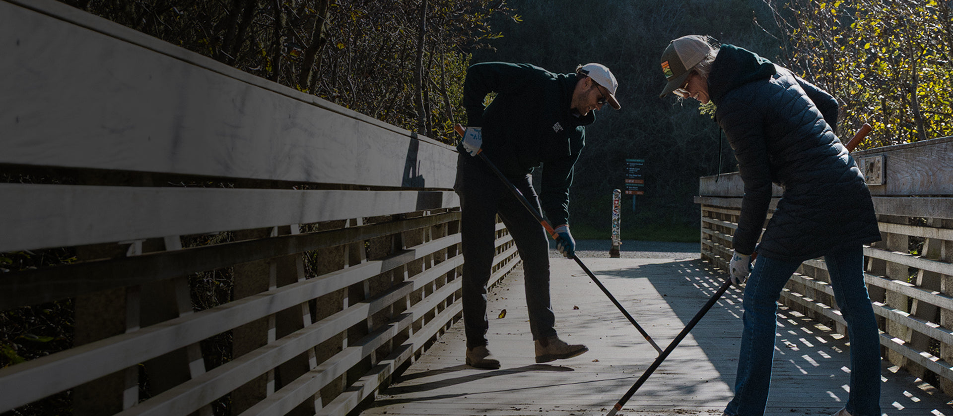 Two people doing maintenance on wooden bridge in a forest