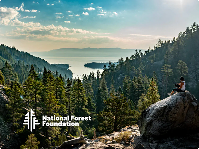 Person sitting on a rock overlooking a forested lake and mountains with National Forest Foundation logo overlay