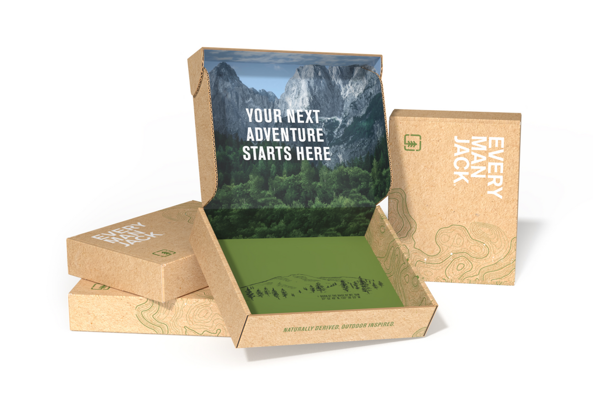 Every Man Jack kraft packaging box showing open interior with mountain print and headline ‘YOUR NEXT ADVENTURE STARTS HERE’