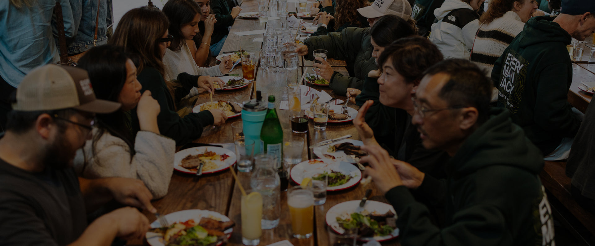 Every Man Jack team members sharing a communal meal at a long wooden table during a company event