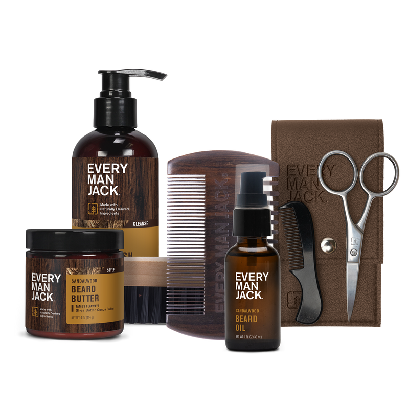 Set of Every Man Jack grooming products including beard butter, beard oil, a wooden comb, scissors, and a brown pouch, labeled with 'Sandalwood' scent.