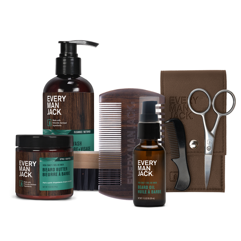 Grooming kit with Every Man Jack beard balm, beard wash, beard oil, a wooden comb, scissors, and a brown carrying case