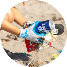 Volunteer wearing a blue glove picking up a crushed can and plastic debris from a sandy beach during a Surfrider cleanup