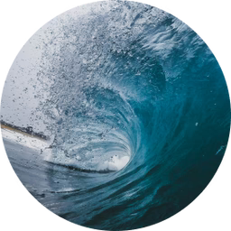 Barrel ocean wave curling toward shore with sandy coastline visible through the wave